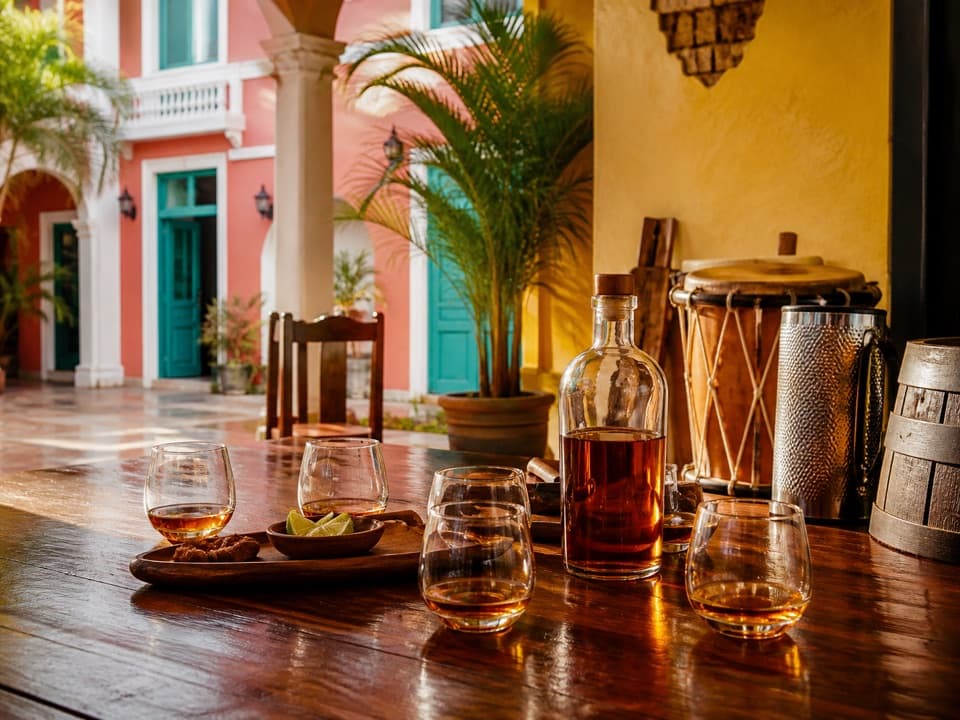 Rum tasting table with amber rum, tambora and güira in a colorful colonial Puerto Plata courtyard.